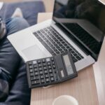 High angle view of a laptop and calculator on a wooden desk with a coffee mug.
